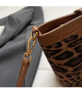 Detail of leopard print fabric bag with brown leather trim and gold lobster clasp hook