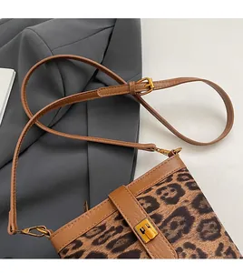 Detail of adjustable brown leather shoulder strap with golden buckle on leopard bucket bag