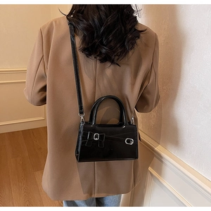 Fashionable black handbag with bow detail shown on a model in a camel blazer outfit