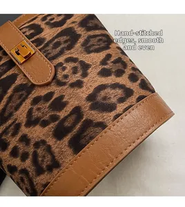 Detail of leopard print suede bag featuring brown leather trim and white hand stitching