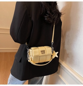 Détail macro du cuir tressé jaune et de la chaîne argentée sur un petit sac carré