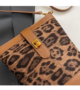 Close-up of leopard print crossbody bag with gold hardware and brown leather trim