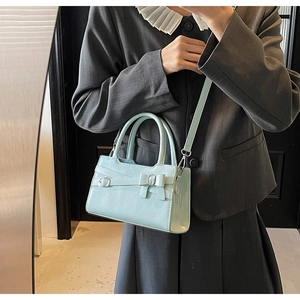 Close-up of light blue leather handbag with silver buckle and decorative bow detailing