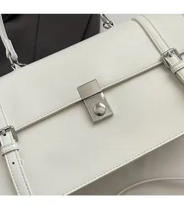 Close-up of silver metal buckle and litchi texture on a white leather shoulder bag