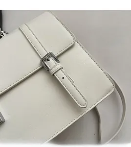 Detailed close-up of cream leather shoulder bag showing fine stitching and silver buckle
