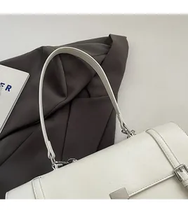 Detailed view of white faux leather bag with silver metal buckle and texture
