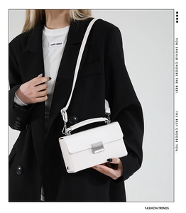 Detailansicht einer weißen Lederhandtasche mit einem silbernen Metall-Steckverschluss