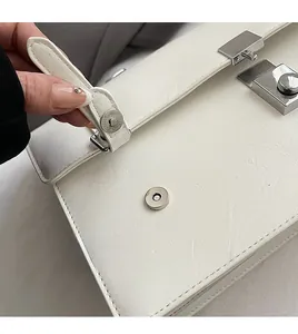 Detail of white lychee texture leather bag featuring silver magnetic closure and buckle