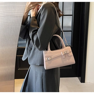 Pink handbag with bow and metal buckle shown in a stylish crossbody handheld pose
