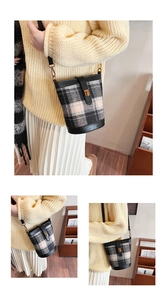 Detail of checkered tweed bucket bag showing leather base and gold metal buckle strap