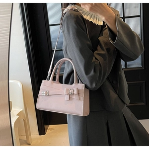 Close-up of light pink glossy handbag featuring a bow design and silver metal buckle