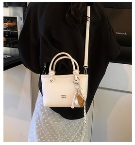 Chic mini borsa a secchiello bianca con manico e tracolla, elegante accessorio quotidiano.