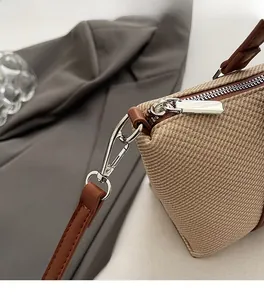 Detail of silver metallic zipper and lobster clasp on beige woven shoulder bag