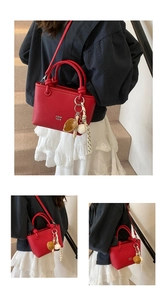Dettaglio borsa a mano in ecopelle rossa con ciondoli da baseball alla moda e tracolla.