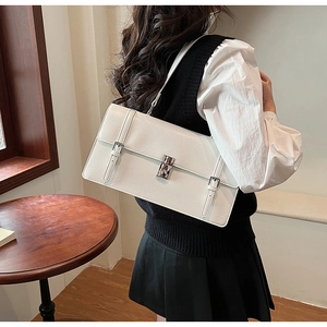 Detailed view of white leather shoulder bag featuring silver metal buckles and square lock