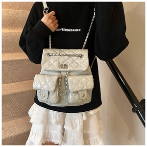 Close-up of quilted mini backpack with metallic chain straps and twist-lock detail