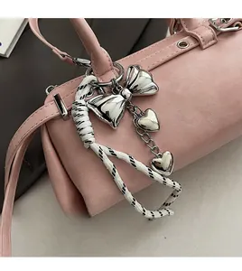 Close-up of pink Boston bag with silver bow, heart pendants and woven rope details