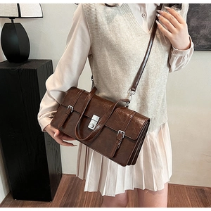Detailed view of a retro brown satchel with metallic square lock and twin buckle straps