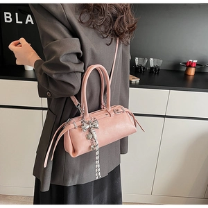 Pink Boston bag detail showing silver bow charm and textured leather on a grey blazer