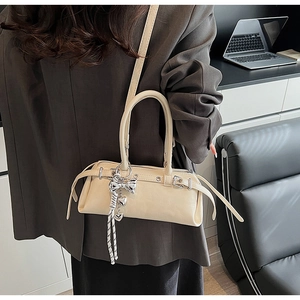 Detail of elegant cream white PU leather handbag with heart pendant and silver bow charm