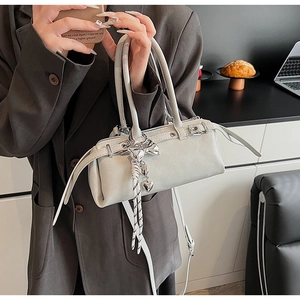 Close-up of light gray leather Boston bag with silver heart and bow pendants