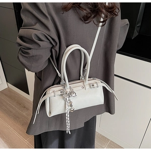 White glossy Boston bag shown worn by model in a minimalist modern setting