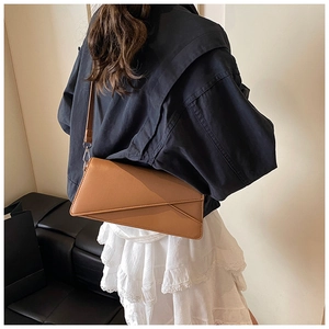 Close-up of caramel leather baguette bag showing geometric envelope flap and fine stitching