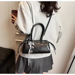 Detail of black Boston bag with silver heart bow pendant and adjustable strap