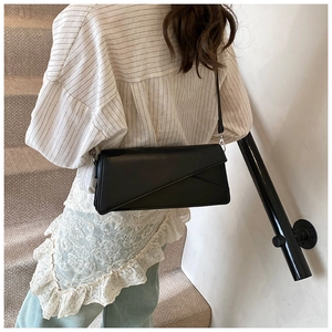 Détail d'un sac bandoulière en cuir noir avec design géométrique porté par un mannequin