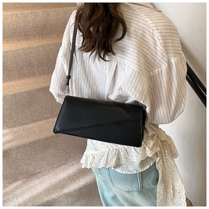 Close-up of a black minimalist leather crossbody bag with geometric geometric stitching