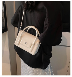 Detailed side view of white faux leather crossbody bag with top handles and logo