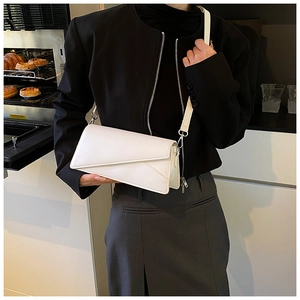 Detail of white PU leather crossbody bag featuring geometric triangle flap and silver buckle