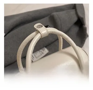 Macro shot of comfortable round handle and silver snap button on creamy white handbag