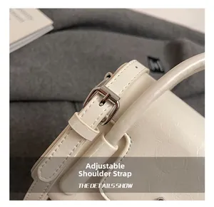 Close-up of the adjustable silver buckle and premium leather texture on white square bag