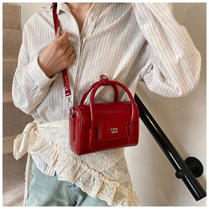 Detail of red small square crossbody bag in glossy oil wax leather with top handles
