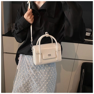 Close-up of a vintage white square handbag with leather texture and metal logo detail