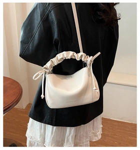Detail of soft cream cloud bag featuring pleated handles and adjustable shoulder strap