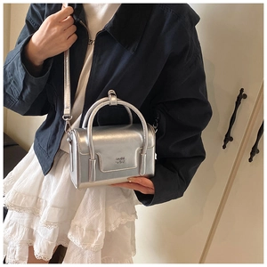 Detail of silver metallic mini bag with SOMN 2DN embossed logo and top handles