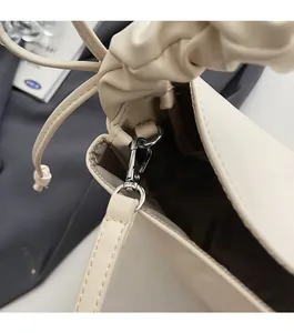 Close-up of silver metal hardware and pleated handle on cream cloud shoulder bag