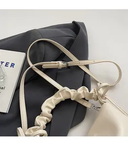 Detail of soft cream leather bag with ruched handle and silver metal hardware accents