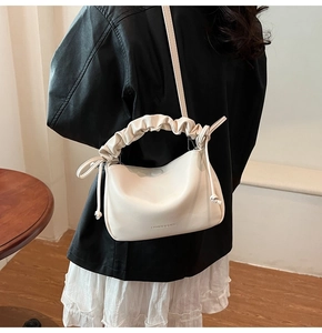 Detail of a creamy white hobo bag showing the ruched handle and embossed fashion text