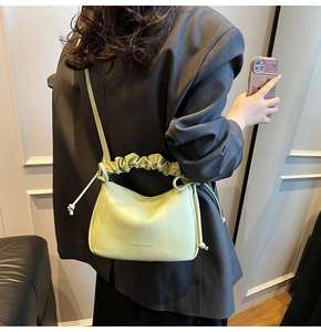 Detail of light green pleated bucket bag showing ruching handle and drawstring accents