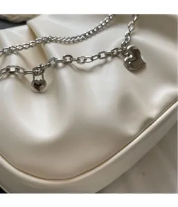 Detail of off-white pleated PU leather bag with silver chain straps and heart pendants
