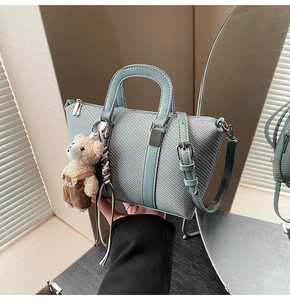 Light blue woven texture bucket bag detail with a cute teddy bear plush charm