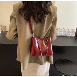Detailansicht der weinroten Lackleder-Eimertasche mit Silberkette an der Modells Schulter