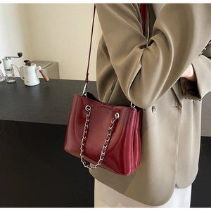 Bordeaux red glossy leather bucket bag with silver chain strap shown with khaki blazer