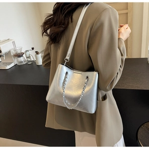 Close-up of a metallic silver bucket bag with chain detail shown on a female model