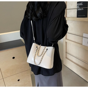 Detailansicht der weißen Lackleder-Beuteltasche mit Silberkette in Wohnambiente