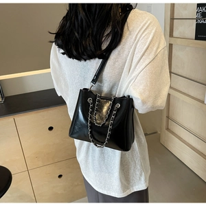 Rear view of a minimalist black shiny leather bucket bag with silver metal chain decor