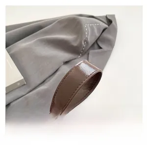 Détail de la bandoulière marron chocolat brillant avec coutures précises du sac à rivets